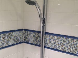 White subway tile with a pop of blue glass mosaics in client’s shower! #subwaytile #njbathremodel #bluetile #showerfixtures #designnj