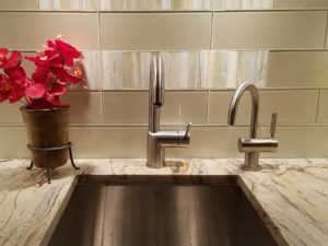 Prada gold granite counters, stainless fixtures and glass subway tile pull our client’s bar sink area together! #njkitchenremodel #granitecountertops #pradagoldgranite #stainlessbarsink #glasssubwaytile #metallicsubwaybacksplash #modernfaucets