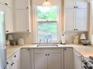 Swipe 👉🏼to see the “before” kitchen. We closed off door on left, relocated the sink under the back window, and moved the new stove and fridge as well.  New floors, double stacked cabinets and stone counters finish this dramatic makeover! #newjerseykitchenandbath #whitekitchen #shakercabinets #kitchenlighting #designnj #kitchenshowroom
