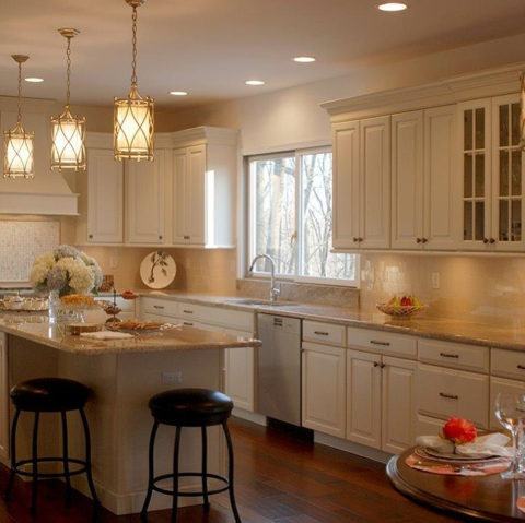 Swipe 👉🏼for a before and after view of our client's newly renovated kitchen! #kitchenlighting #newjerseykitchenandbath #designnj #newjerseykitchenmakeover #maplecabinets #whitekitchen #granitecountertops #backsplashtile #woodflooring